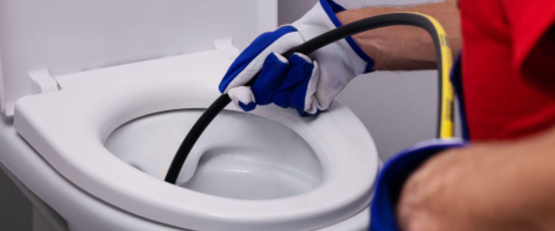 Técnico realizando desentupimento de vaso sanitário